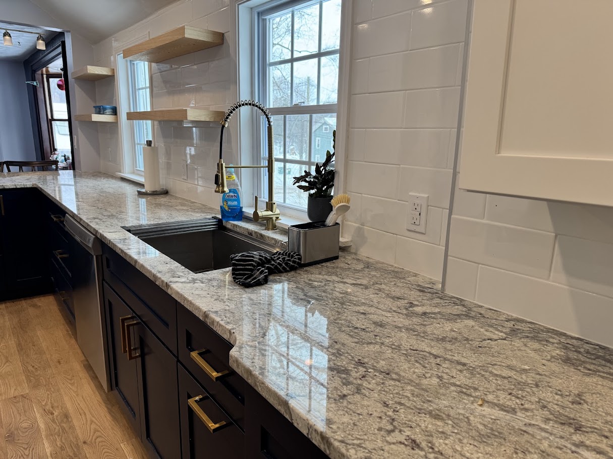 Elegant Kitchen with Brass Fixtures - Brass faucet, subway tile backsplash, and custom floating shelves.